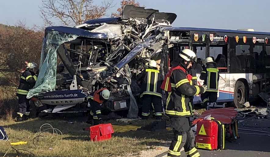 Firefighters stand next to buses crashed in Ammerndorf near Fuerth, Germany, Thursday, Nov. 15, 2018. 15.11.2018. Police say 40 adults and children have been injured, five of them “very seriously,” after two public buses collided. (Michl Schmelzer/dpa via AP)