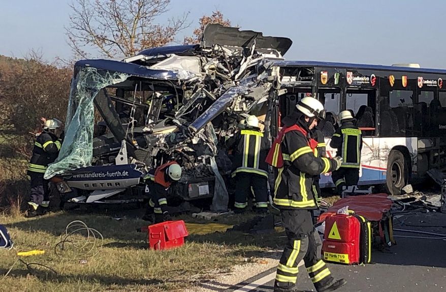 Firefighters stand next to buses crashed in Ammerndorf near Fuerth, Germany, Thursday, Nov. 15, 2018. 15.11.2018. Police say 40 adults and children have been injured, five of them “very seriously,” after two public buses collided. (Michl Schmelzer/dpa via AP)