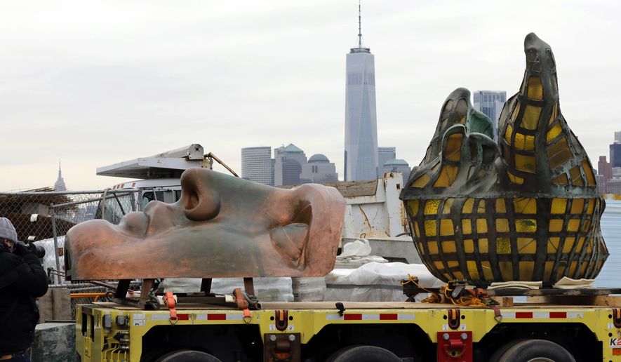 The original torch of the Statue of Liberty, and a replica of her face, rest on a hydraulically stabilized transporter, Thursday, Nov. 15, 2018 in New York. The torch, which was removed in 1984 and replaced by a replica, was being moved into what will become its permanent home at a new museum on Liberty Island. New York&#x27;s One World Trade Center is visible, background center. (AP Photo/Richard Drew)