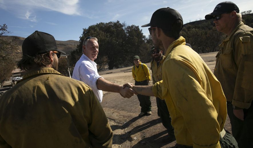 U.S. Secretary of the Interior Ryan Zinke, second from left, shakes hands with firefighters while visiting decimated Paramount Ranch Thursday, Nov. 15, 2018, in Agoura Hills, Calif. The landmark film location burned to the ground by the Woolsey Fire. (AP Photo/Jae C. Hong)