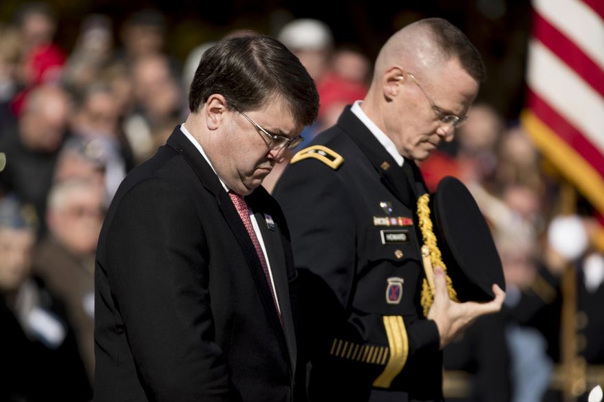 Veterans Affairs Secretary Robert Wilkie, left, lowers his head after placing a wreath at the Tomb of the Unknown Soldier during a ceremony at Arlington National Cemetery on Veterans Day, Sunday, Nov. 11, 2018, in Arlington, Va. (AP Photo/Andrew Harnik)