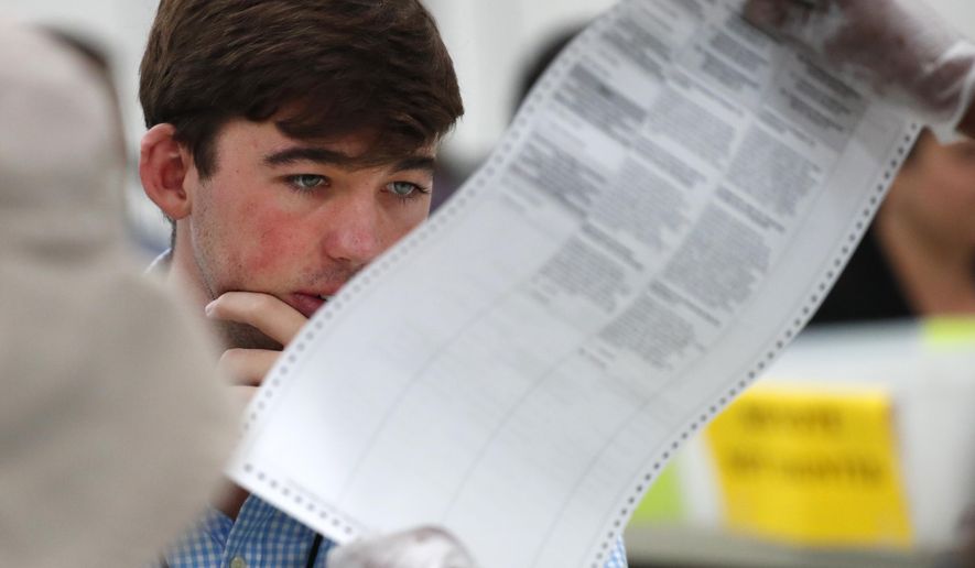 A Republican observer looks at a ballot during a hand recount, Friday, Nov. 16, 2018, at the Broward County Supervisor of Elections office in Lauderhill, Fla. Florida's acrimonious U.S. Senate contest is headed to a legally required hand recount after an initial review by ballot-counting machines showed Republican Gov. Rick Scott and Democratic Sen. Bill Nelson separated by fewer than 13,000 votes. (AP Photo/Wilfredo Lee)