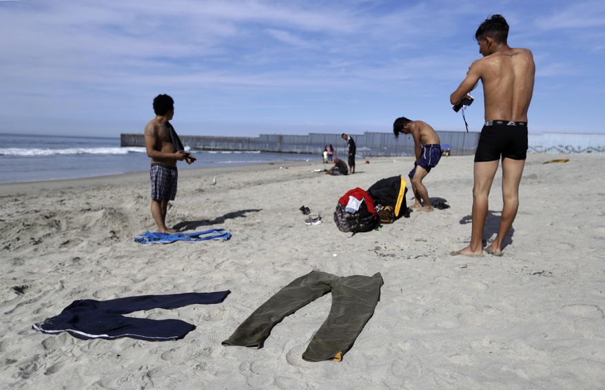 Migrants from Honduras dry their clothes in the sand after washing off in the Pacific Ocean, near the border fence in Tijuana, Mexico, Thursday, Nov. 15, 2018. Members of a migrant caravan from Central America started to meet some local resistance as they continued to arrive by the hundreds in the Mexican border city of Tijuana, where a group of residents clashed with migrants camped out by the U.S. border fence. (AP Photo/Gregory Bull)