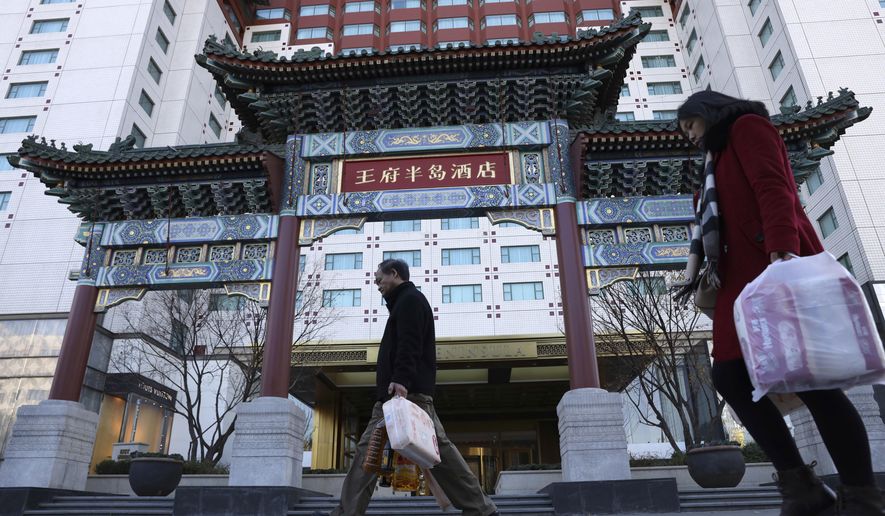 Residents passes by The Peninsula hotel which announced that it was investigating claims in an online video that supposedly showed the hotel cleaners using dirty towels to wipe cups and sinks in Beijing Friday, Nov. 16, 2018. The Chinese tourism ministry asked authorities in Beijing, Shanghai and three provinces to investigate room cleaning at 14 major hotels after hidden camera video showed workers using used towels to clean cups and glasses and other questionable practices. (AP Photo/Ng Han Guan)