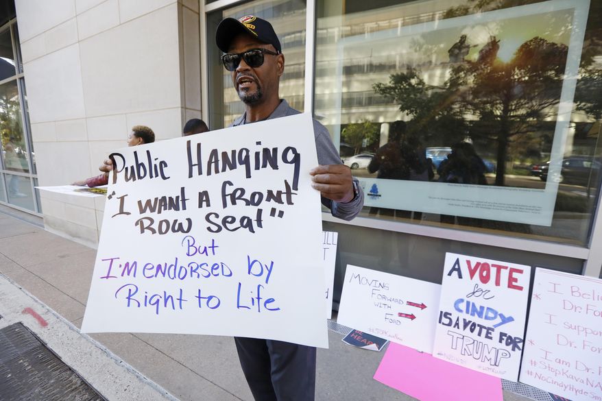 George H. Williams of Ridgeland, Miss., holds a protest sign outside the downtown complex that houses the offices of appointed U.S. Sen. Cindy Hyde-Smith, R-Miss., on Friday, Nov. 16, 2018, in Jackson, Miss. Williams, a Marine Corps veteran, said he was upset with comments Hyde-Smith made about "public hanging" and voting rights. Hyde-Smith and Democrat Mike Espy are competing to serve the final two years of a six-year term started by Republican Thad Cochran, who retired. (AP Photo/Rogelio V. Solis)
