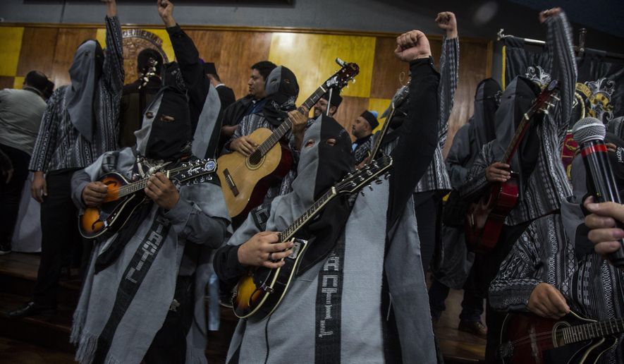 Students of the University of San Carlos wearing hoods, sing protests songs during the ceremony to present Bolivia's president Evo Morales with a Honorary Doctorate, at the University of Guatemala, Thursday, Nov. 15, 2018. Morales is in Guatemala for the XXVI Iberoamerican Summit that is taking place in Antigua. (AP Photo/Oliver de Ros)