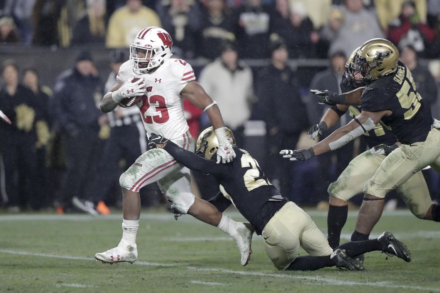 Wisconsin running back Jonathan Taylor (23) breaks the tackle of Purdue safety Navon Mosley (27) on his way to scoring a game-winning touchdown during overtime of an NCAA college football game in West Lafayette, Ind., Saturday, Nov. 17, 2018. Wisconsin defeated Purdue 47-44 in overtime. (AP Photo/Michael Conroy)