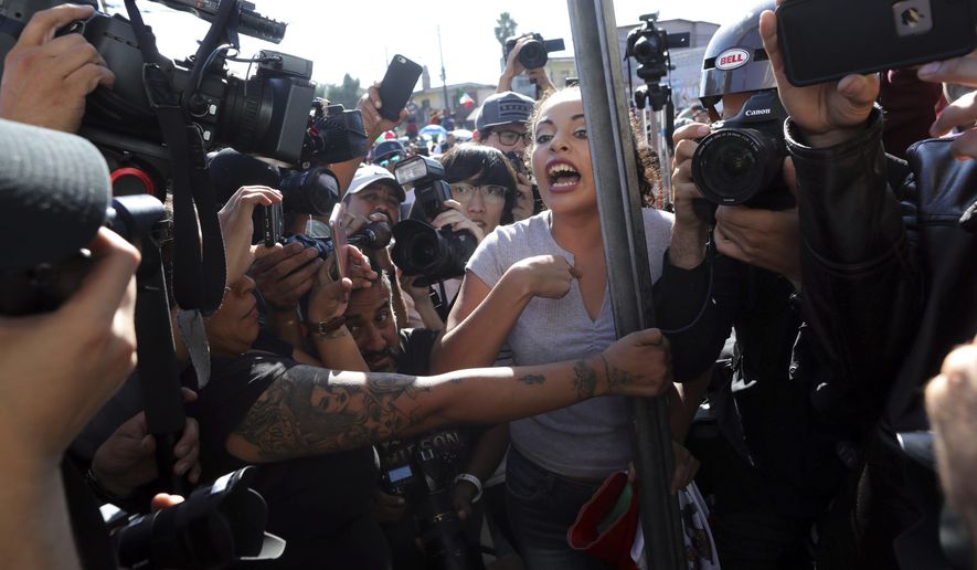 An anti-migrant demonstrator is surrounded by the press as she argues with a woman during a protest against the presence of thousands of Central American migrants in Tijuana, Mexico, Sunday, Nov. 18, 2018. Protesters accused the migrants of being messy, ungrateful and a danger to Tijuana; complained about how the caravan forced its way into Mexico, calling it an &amp;quot;invasion,&amp;quot; and voiced worries that their taxes might be spent to care for the group as they wait possibly months to apply for U.S. asylum. (AP Photo/Rodrigo Abd)