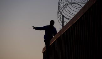 A Mexican citizen gestures after climbing the border fence to take pictures of himself, in Tijuana, Mexico, Sunday, Nov. 18, 2018. (AP Photo/Ramon Espinosa)