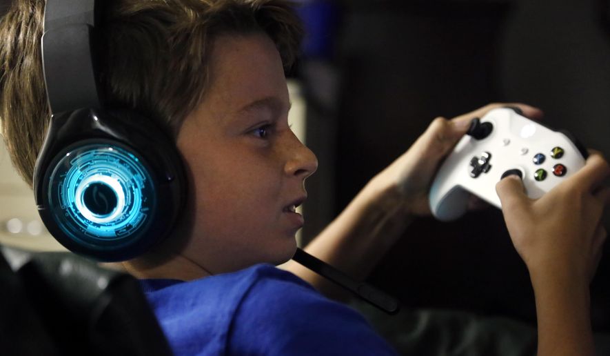 In this Saturday, Oct. 6, 2018, photo, Henry Hailey, 10, plays the online game Fortnite in the early morning hours in the basement of his Chicago home. His parents are on a quest to limit screen time for him and his brother. The boys say they understand sometimes, but also complain that they get less screen time than their friends. (AP Photo/Martha Irvine)