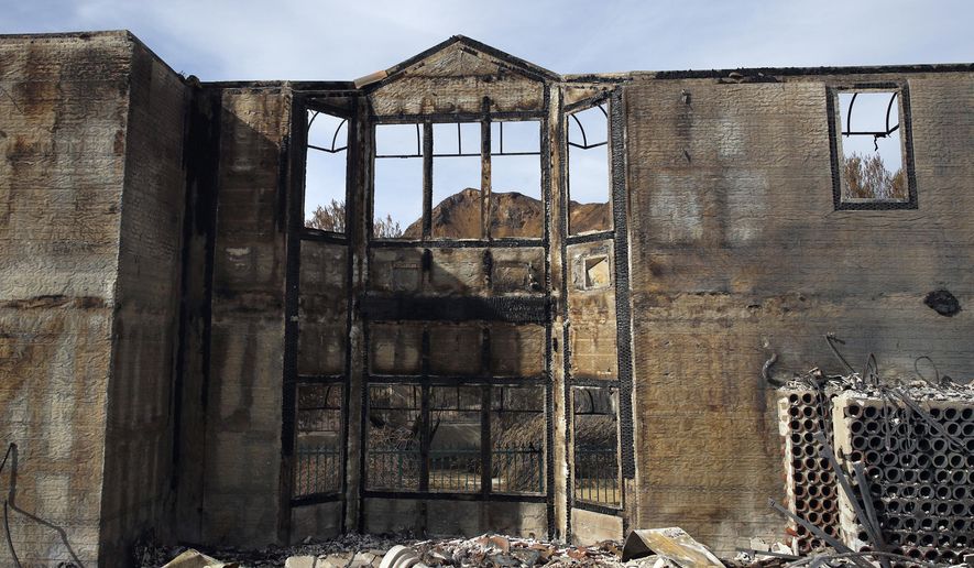 FILE - This Nov. 13, 2018 file photo shows the charred window frames of a mansion destroyed by the Woolsey fire in Agoura Hills, Calif. The number of structures destroyed by a huge Southern California wildfire has risen to 1,500. Another 341 structures were damaged as of a Monday, Nov. 20, 2018 count. As firefighters mop up, repair and restoration of utilities is continuing along with repopulation of areas. (AP Photo/Jae C. Hong)