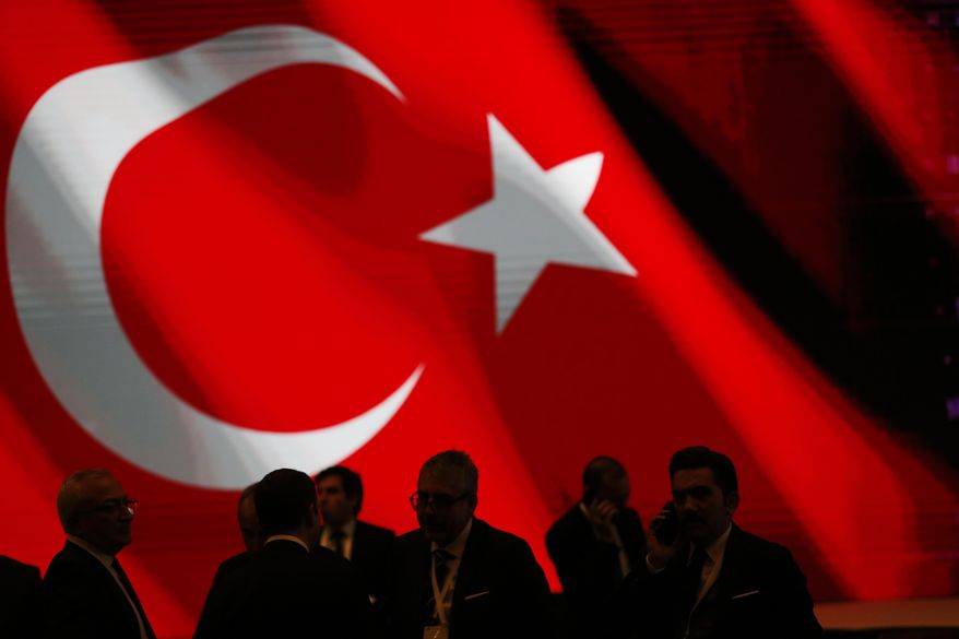 Backdropped by Turkey&#39;s flag officials wait for an event to be attended by Turkey&#39;s President Recep Tayyip Erdogan and Russian President Vladimir Putin, marking the completion of one of the phases of the Turkish Stream natural gas pipeline, in Istanbul, Monday, Nov. 19, 2018.  The two 930-kilometer (578-mile) lines when finished are expected to carry 31.5 billion cubic meters (1.1 trillion cubic feet) of Russian natural gas annually to European markets, through Turkish territories.(AP Photo/Lefteris Pitarakis)