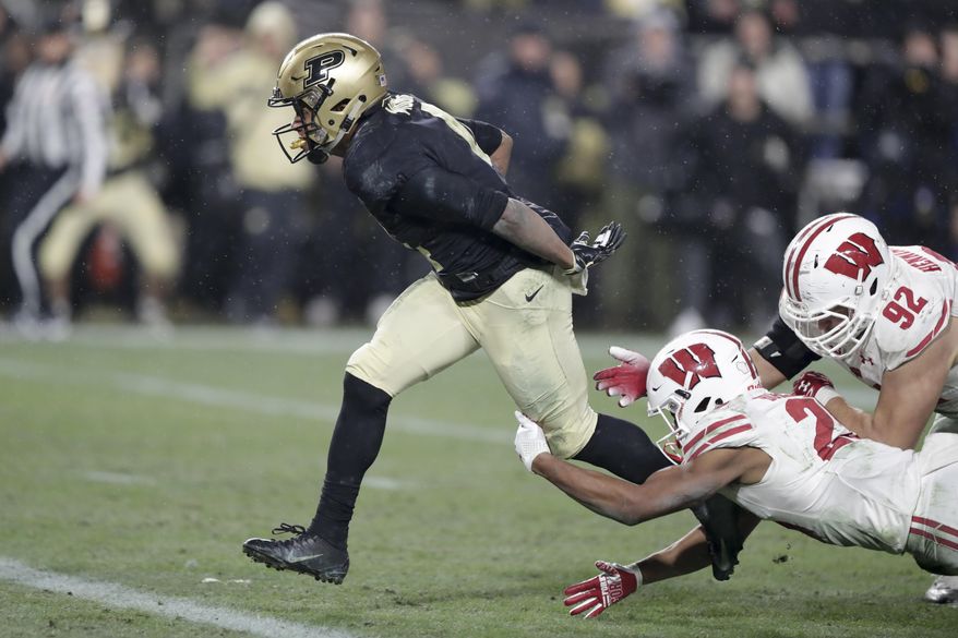 Purdue wide receiver Rondale Moore (4) breaks the tackle of Wisconsin defensive end Matt Henningsen (92) and safety Eric Burrell (25) on his way to a touchdown during overtime of an NCAA college football game in West Lafayette, Ind., Saturday, Nov. 17, 2018. Wisconsin defeated Purdue 47-44 in overtime. (AP Photo/Michael Conroy)