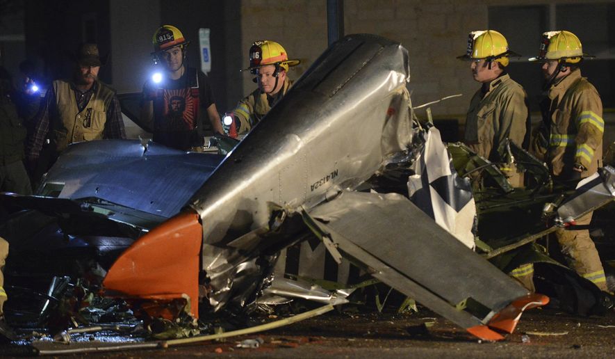 In this Saturday, Nov. 17, 2018, photo firefighters and investigators look over a vintage World War II P-51D Mustang aircraft after a deadly crash in Fredericksburg, Texas. (Billy Calzada/The San Antonio Express-News via AP)