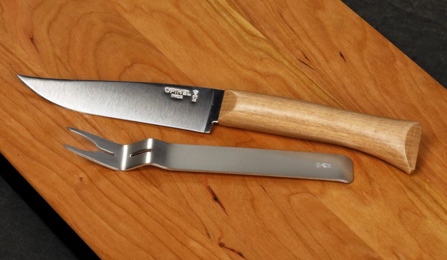 This Nov. 13, 2018 photo shows an Opinel Cheese Knife and Fork Set on a JK Adams Cherry Cheese Server in New York. It is a compact set of an interlocking fork and cheese knife made from stainless steel and a blond beech-wood handle. (AP Photo/Richard Drew)