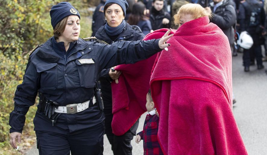 A woman evicted from one of eight illegally built villas belonging to members of the Casamonica criminal clan, is escorted by two police officers, in Rome, Tuesday, Nov. 20, 2018. Rome city authorities sent in 600 police officers to evict a purported crime family from eight villas that were allegedly built without authorization decades ago. (Massimo Percossi/ANSA via AP)