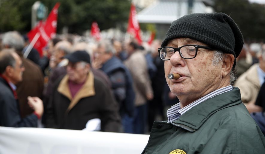 An elderly man smokes a cigar during a rally in Athens, Tuesday, Nov. 20, 2018. Hundreds of pensioners protested demanding a return of funds lost as part of austerity measures. (AP Photo/Thanassis Stavrakis)