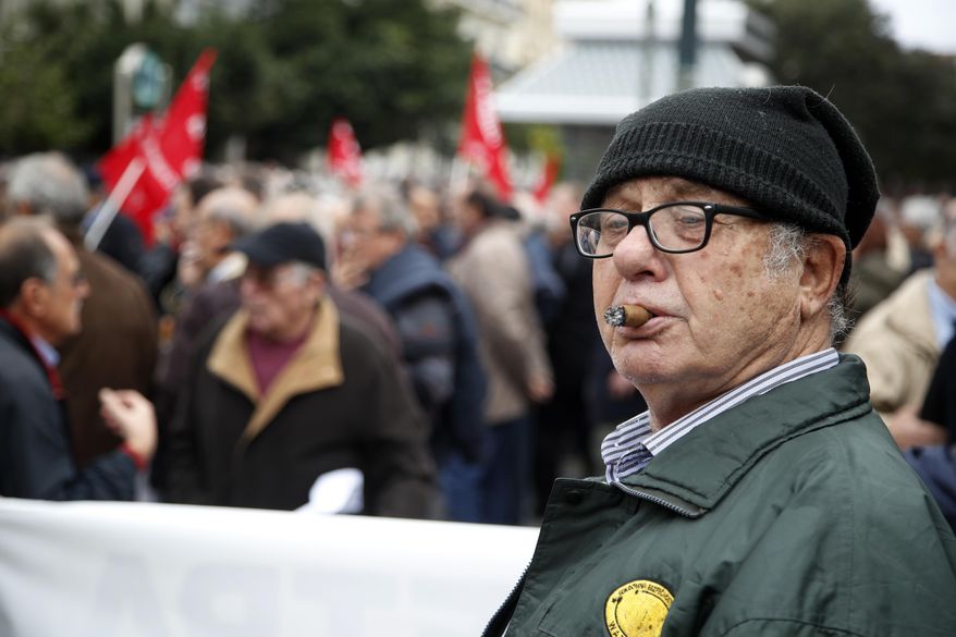 An elderly man smokes a cigar during a rally in Athens, Tuesday, Nov. 20, 2018. Hundreds of pensioners protested demanding a return of funds lost as part of austerity measures. (AP Photo/Thanassis Stavrakis)