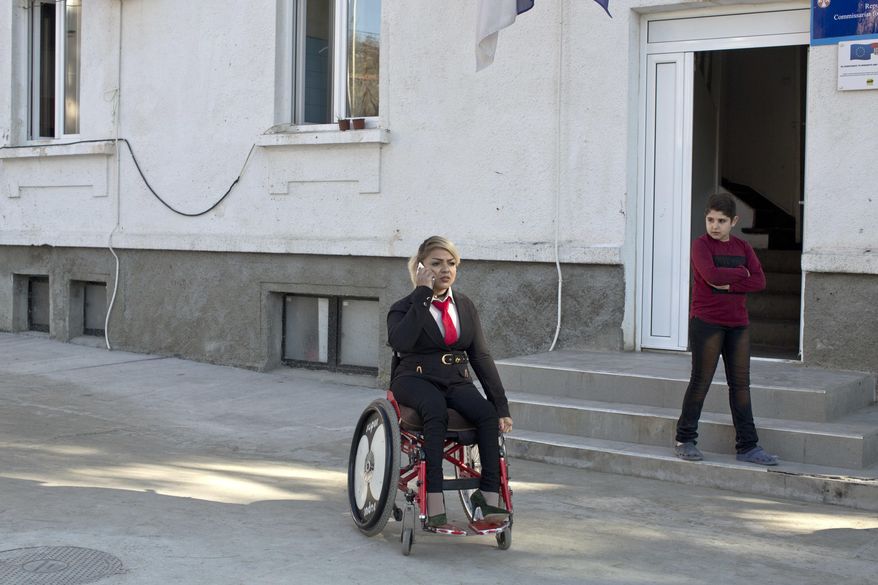 In this photo taken Tuesday, Nov. 13, 2018, Mahana Jami, 34, center, talks on the phone while inside a government run camp for refugees and migrants in Bosilegrad, some 250 kilometers southeast of Belgrade, Serbia. As a little girl in a wheelchair in Iran, Jami used to watch other children play on a slide and wondered why she couldn't do the same. She then made a promise to herself to always dream big and never let her disability stand in the way. (AP Photo/Marko Drobnjakovic)