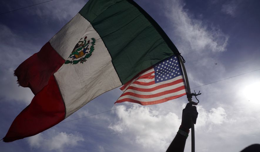 A Honduran migrant holds up Mexican and U.S. flags as he joins a small group of migrants trying to cross the border together at the Chaparral border crossing in Tijuana, Mexico, Thursday, Nov. 22, 2018. (AP Photo/Ramon Espinosa) ** FILE **