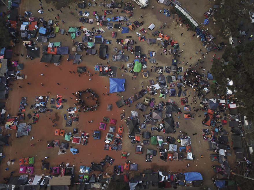 Central American migrants gather in an area designated for them to set up their tents in Tijuana, Mexico, Wednesday, Nov. 21, 2018. Migrants camped in Tijuana after traveling in a caravan to reach the U.S are weighing their options after a U.S. court blocked President Donald Trump's asylum ban for illegal border crossers. (AP Photo/Rodrigo Abd)