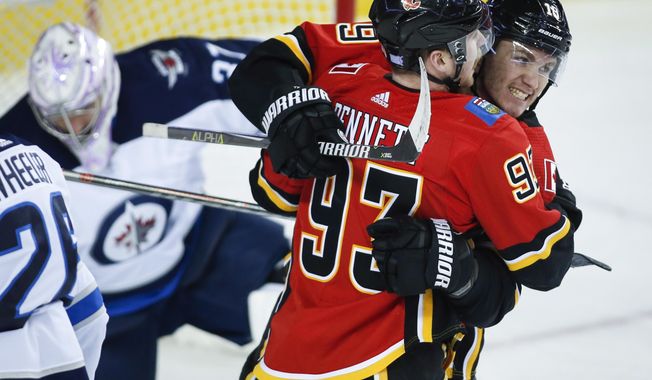 Calgary Flames&#x27; Sam Bennett (93) celebrates his goal with teammate Matthew Tkachuk, right, as Winnipeg Jets goalie Connor Hellebuyck picks himself up during the first period of an NHL hockey game Wednesday, Nov. 21, 2018, in Calgary, Alberta. (Jeff McIntosh/The Canadian Press via AP)