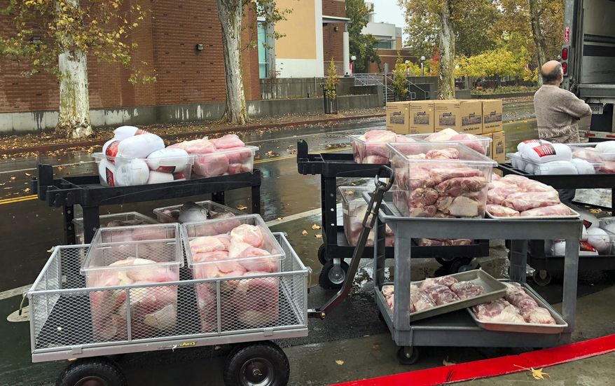 Hundreds of frozen turkeys are unloaded on the campus of California State University, in Chico, Calif., Wednesday, Nov. 21, 2018. The nonprofit World Central Kitchen is preparing them for a Thanksgiving meal for residents displaced by the Camp Fire in Northern California. The fire ignited Nov. 8 and devastated Paradise, Calif., and surrounding communities. (AP Photo/Kathleen Ronayne)