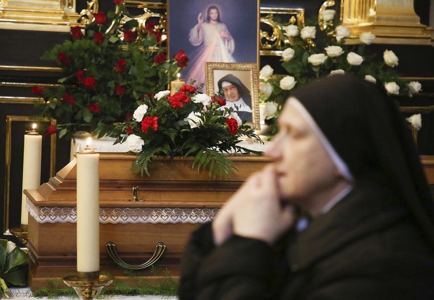 A nun prays beside the casket and photo of 110-year-old Roman Catholic Sister Cecylia Roszak, believed to be the world's oldest nun, and a rescuer of Jews during the Holocaust, during her funeral ceremonies at Church of Our Lady of the Snows the Dominican in Krakow, Poland, Thursday, Nov. 22, 2018. She died the previous week at a Dominican convent in Krakow. (AP Photo/Beata Zawrzel)