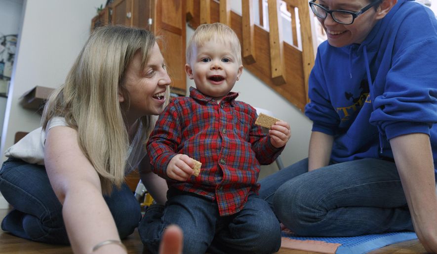In this Friday, Nov. 16, 2018, photo, Anna Ford, left, and her partner, Sara Watson, play with their son Eli at home in the village of Saunderstown, in Narragansett, R.I. Three years after the landmark U.S. Supreme Court case that gave same-sex couples the right to marry nationwide, a patchwork of outdated state laws governing who can be a legal parent presents obstacles for many LGBTQ couples who start a family, lawyers say. (AP Photo/Michael Dwyer)