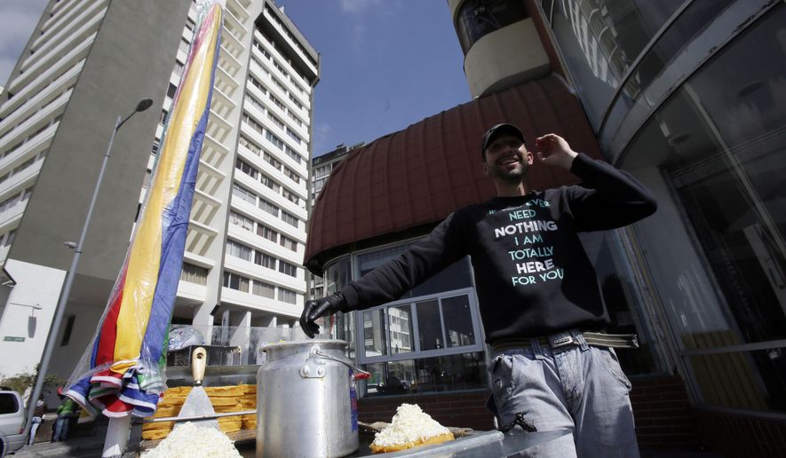 A Venezuelan migrant named Renzo sell arepas, a Venezuelan cornmeal cake, at a street corner in Quito, Ecuador, Thursday, Nov. 22, 2018. Renzo claims that he worked as an electrical engineer back in Venezuela, but now sells arepas to maintain his family that emigrated with him to Ecuador. (AP Photo/Dolores Ochoa)