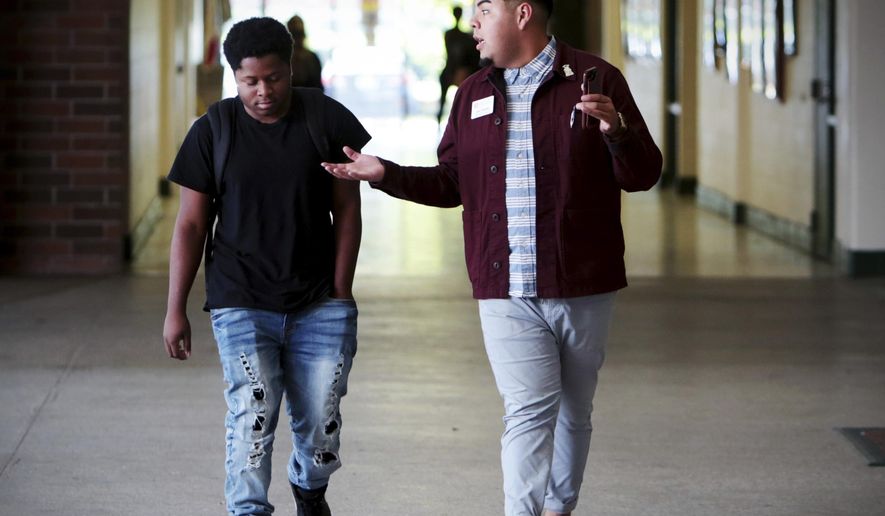 In this Oct. 18, 2018 photo, Jose Alvarez, right, speaks with Eastside High School student and Take Stock in Children participant Jakari Spikes, 17, in Gainesville, Fla. Rural students are far less likely than urban and suburban peers to go to college, and the divide is growing deeper in places across Florida. Alvarez is a student advocate for Take Stock in Children, he spends the majority of his days talking to students about college options and graduation. (Tailyr Irvine/Tampa Bay Times via AP)