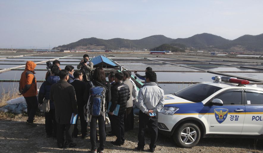 FILE - In this Feb. 19, 2014, file photo, lawmakers and human right activists look at salt farms as a part of human rights inspection on Sinui Island, South Korea. A South Korean court has ruled on Friday, Nov. 2, 2018, that the government must pay 80 million won ($70,000) to three men who were enslaved on salt farms in remote islands off the country's southwest coast for several years. (AP Photo/Ahn Young-joon, File)
