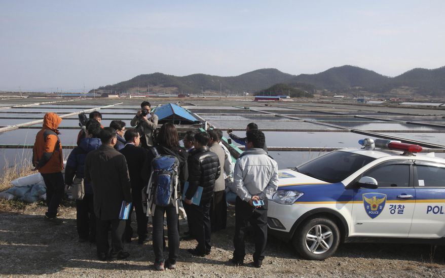 FILE - In this Feb. 19, 2014, file photo, lawmakers and human right activists look at salt farms as a part of human rights inspection on Sinui Island, South Korea. A South Korean court has ruled on Friday, Nov. 2, 2018, that the government must pay 80 million won ($70,000) to three men who were enslaved on salt farms in remote islands off the country's southwest coast for several years. (AP Photo/Ahn Young-joon, File)