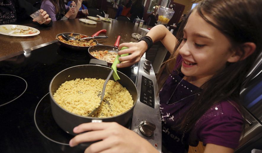 ADVANCE FOR RELEASE SATURDAY, NOVEMBER 24, 2018 Kaydey Plate, 11, of Fort Madison stirs Yellow Basmati Rice Wednesday Nov. 14, 2018 at Elliott Test Kitchen in Fort Madison, Iowa. You can find her picture and details of the recipe in the cookbook by the students titled "Elliott Test Kitchen Young Chefs." (John Gaines/The Hawk Eye via AP)