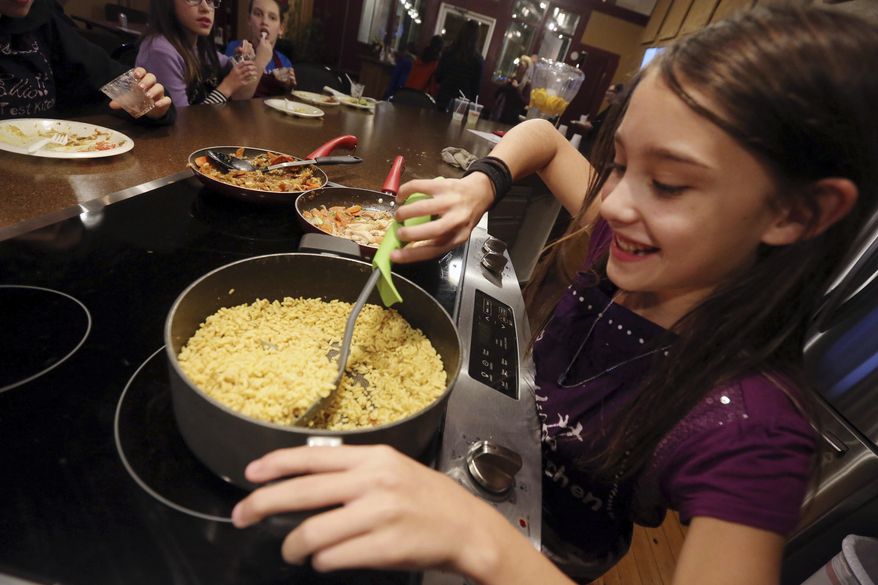 ADVANCE FOR RELEASE SATURDAY, NOVEMBER 24, 2018 Kaydey Plate, 11, of Fort Madison stirs Yellow Basmati Rice Wednesday Nov. 14, 2018 at Elliott Test Kitchen in Fort Madison, Iowa. You can find her picture and details of the recipe in the cookbook by the students titled "Elliott Test Kitchen Young Chefs." (John Gaines/The Hawk Eye via AP)