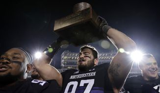 Northwestern defensive line Joe Gaziano, center, celebrates with teammates as he holds the Land of Lincoln Trophy after Northwestern defeated Illinois 24-16 in an NCAA college football game in Evanston, Ill., Saturday, Nov. 24, 2018. (AP Photo/Nam Y. Huh)