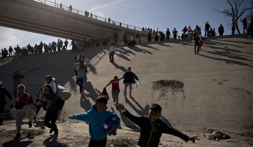 Migrants cross the river at the Mexico-U.S. border after pushing past a line of Mexican police at the Chaparral crossing in Tijuana, Mexico, Sunday, Nov. 25, 2018, as they try to reach the U.S.  The mayor of Tijuana has declared a humanitarian crisis in his border city and says that he has asked the United Nations for aid to deal with the approximately 5,000 Central American migrants who have arrived in the city. (AP Photo/Ramon Espinosa)