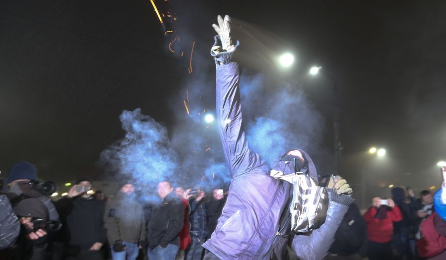 A protester throws a smoke grenade during a rally in front of the embassy of Russia in Kiev, Ukraine, Sunday, Nov. 25, 2018. Russia&#x27;s coast guard opened fire on and seized three of Ukraine&#x27;s vessels Sunday, wounding two crew members, after a tense standoff in the Black Sea near the Crimean Peninsula, the Ukrainian navy said. (AP Photo/Efrem Lukatsky)