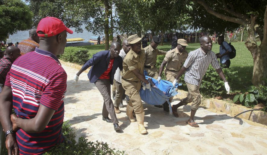 Ugandan police carry away a body of one of the victims of a boat which capsized in Lake Victoria near the capital, Kampala, Uganda, Sunday, Nov. 25, 2018. Police say dozens died when the boat, which was carrying more than 90 passengers on a pleasure cruise, capsized Saturday evening. (AP Photo/Stephen Wandera)
