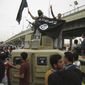 In this Sunday, March 30, 2014, file photo, Islamic State group militants hold up their flag as they patrol in a commandeered Iraqi military vehicle in Fallujah, 40 miles (65 kilometers) west of Baghdad, Iraq. (AP Photo, File)