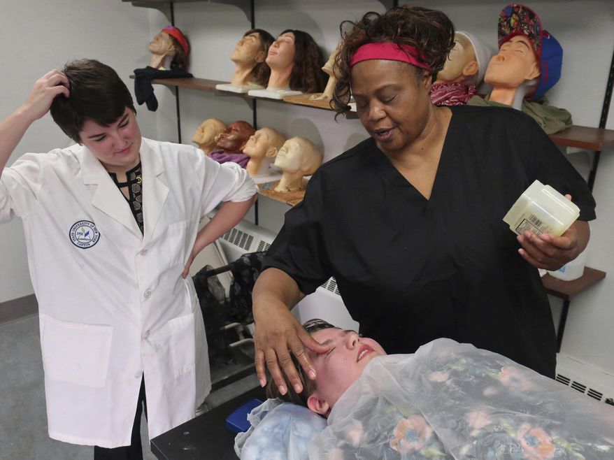 In this Monday, Oct. 22, 2018, photo, funeral services students Maeve Curran, left, and Anita Bennett start to build a life mask on fellow student Anna Deloriea at State University of New York at Canton. By measuring facial dimensions and symmetry, students learn how to restore facial features lost to illness or trauma on the deceased. Eighty percent of the undergraduate funeral director students at this school are female, mirroring a nationwide trend. (AP Photo/Ted Shaffrey)