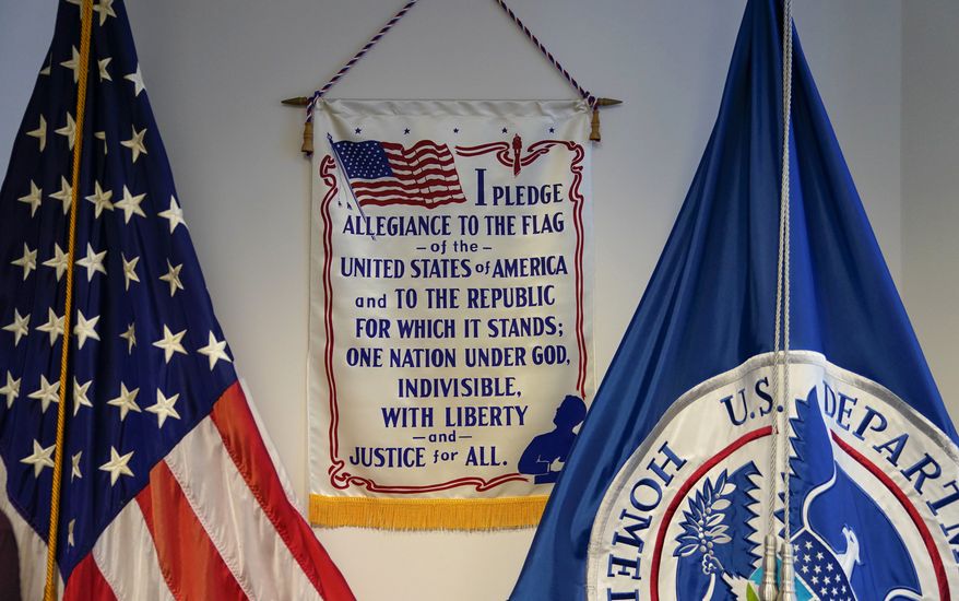 The Pledge of Allegiance is located at the front of the room where 106-year old Maria Valles Bonilla will recite the Oath of Allegiance for a naturalization ceremony at U.S. Citizenship and Immigration Services office Tuesday, Nov. 6, 2018, in Fairfax, Va. Bonilla is from El Salvador and it was her late husband's dream to become a U.S. citizen, so today she became a citizen for both of them. (AP Photo/Pablo Martinez Monsivais)