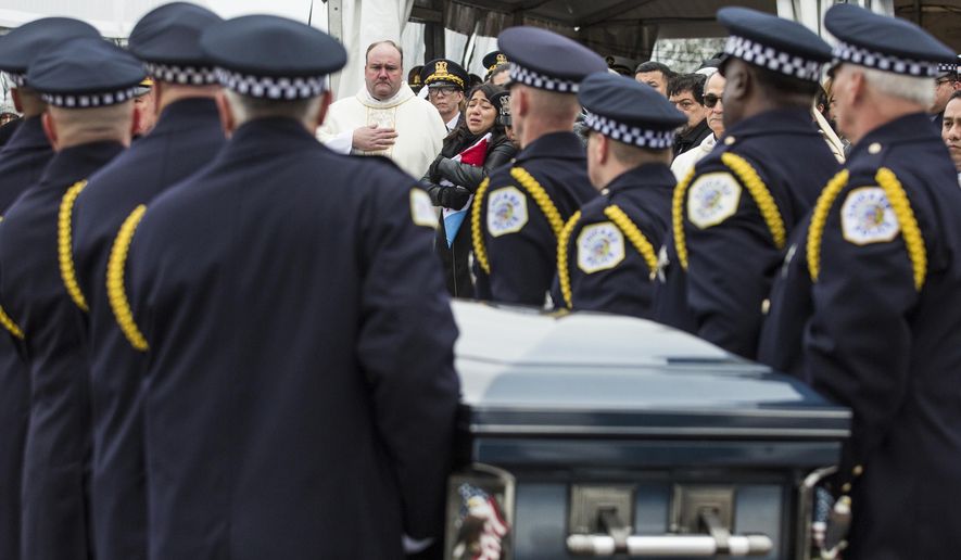Chicago Police Officer Samuel Jimenez's wife, Crystal Garcia, back center, watches as pallbearers place his casket into the hearse after the funeral at Chapel of St. Joseph at Shrine of Our Lady of Guadalupe in Des Plaines, Monday, Nov. 26, 2018. Jimenez was killed by a gunman at Mercy Hospital on Nov. 19. (Ashlee Rezin/Chicago Sun-Times via AP)