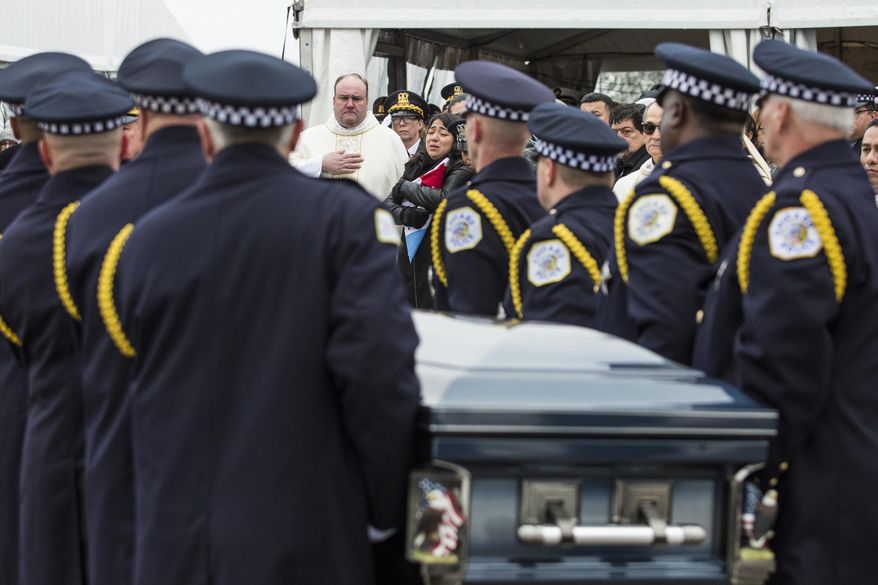 Chicago Police Officer Samuel Jimenez's wife, Crystal Garcia, back center, watches as pallbearers place his casket into the hearse after the funeral at Chapel of St. Joseph at Shrine of Our Lady of Guadalupe in Des Plaines, Monday, Nov. 26, 2018. Jimenez was killed by a gunman at Mercy Hospital on Nov. 19. (Ashlee Rezin/Chicago Sun-Times via AP)
