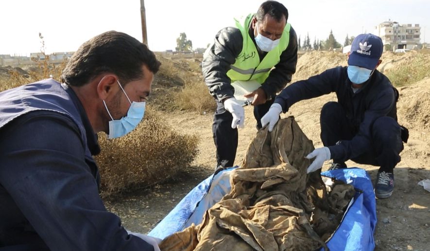 This frame grab from a video provided on Thursday, Nov. 22, 2018, shows a Syrian worker of a Raqqa group checking human remains at the site of a mass grave believed to contain the bodies of civilians and Islamic State militants, in Raqqa. A local official in the city of Raqqa says more than 500 bodies have so far been exhumed from one of the largest mass graves discovered in the city. The northern Syrian city was once the de facto capital of the Islamic State group and was liberated in a campaign that ended more than a year ago, but rescuers and early recovery teams continue to locate mass graves scattered around the city. (AP Photo)