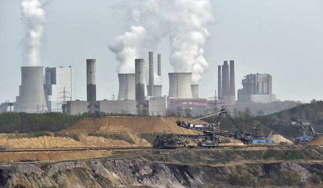In this April 3, 2014, file photo giant machines dig for brown coal at the open-cast mining Garzweiler in front of a smoking power plant near the city of Grevenbroich in western Germany. Despite uncertainties about whether the United States will remain committed to the Paris climate accord under President Donald Trump, diplomats convened talks in Bonn, Germany, Monday, May 8, 2017 on implementing the details of the global deal to combat global warming. (AP Photo/Martin Meissner, File)