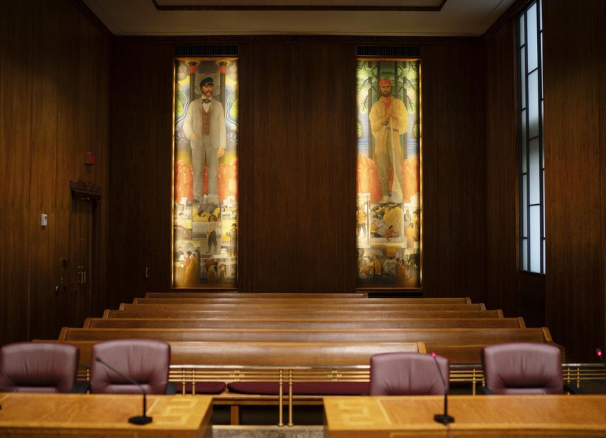 This Nov. 20, 2018, photo shows two pieces of murals displayed in the City Council chambers of the city hall in St. Paul. Officials in St. Paul are rethinking murals from the 1930s that line the walls of the City Council chambers. The City Council and Ramsey County Board are expected to vote next month to start the process of commissioning new murals to temporarily cover the old ones. The Star Tribune reports the new murals will rotate in and out of the chambers, allowing visitors to see them alongside the original works. Chicago artist John Norton painted the murals. (Jeff Wheeler/Star Tribune via AP)