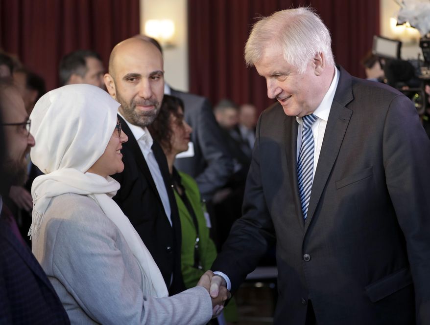 German Interior Minister Horst Seehofer, right, shakes hands with a participant as he arrives for the 4th German Islam Conference in Berlin, Germany, Wednesday, Nov. 28, 2018. (AP Photo/Michael Sohn)