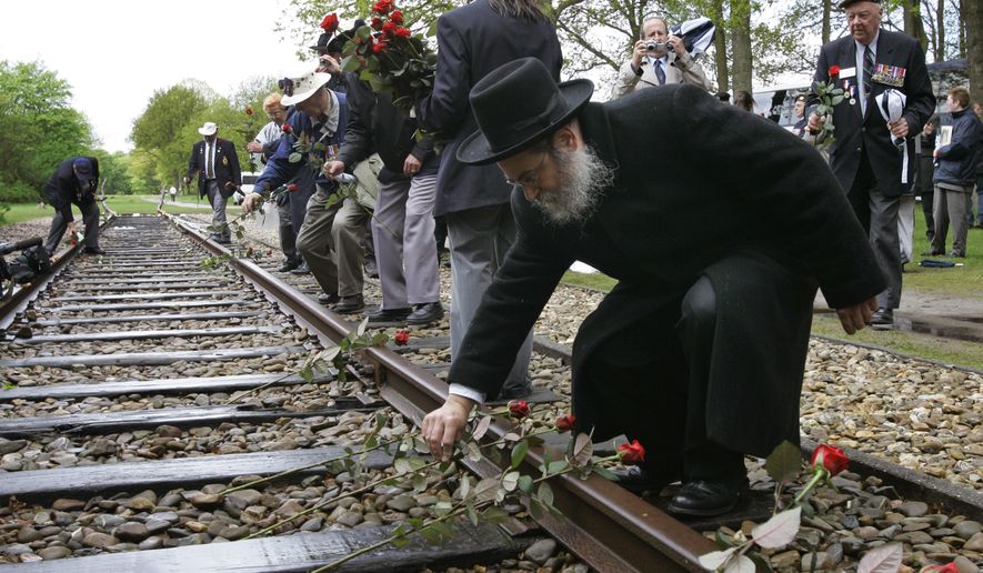 In this Monday May 9, 2015, file photo, a Rabbi puts a rose on the railroad tracks at former concentration camp Westerbork, the Netherlands, remembering more than a hundred thousand Jews who were transported from Westerbork to Nazi death camps. The Dutch national railway company NS says it will set up a commission to investigate how it can pay individual reparations for its role in mass deportations of Jews by Nazi occupiers during World War II. (AP Photo/Peter Dejong)