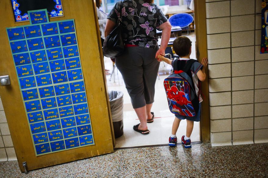 FILE - In this Sept. 8, 2015 file photo, a reluctant student is pulled into the first day of kindergarten at an elementary School in Clio, Mich. A study shows the youngest children in a classroom are more likely to be diagnosed with attention deficit hyperactivity disorder. It’s an intriguing finding for parents considering what’s called “kindergarten redshirting,” or delaying school entry. Researchers say doctors should be aware of how classroom comparisons shape diagnosis. The paper was published Wednesday, Nov. 28, 2018, by the New England Journal of Medicine. (Christian Randolph/The Flint Journal via AP, File)
